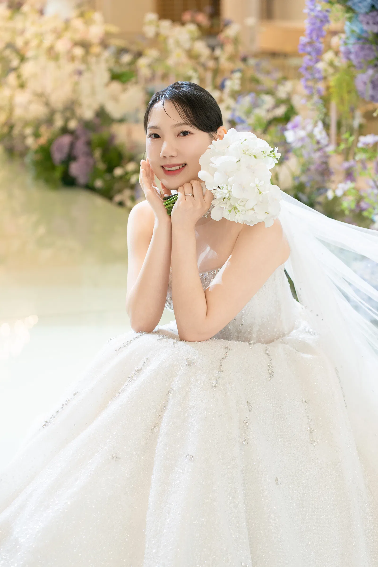 라마다호텔 송도점 꽃장식 앞에서 부케를 얼굴 옆에 들고 앉은 신부
