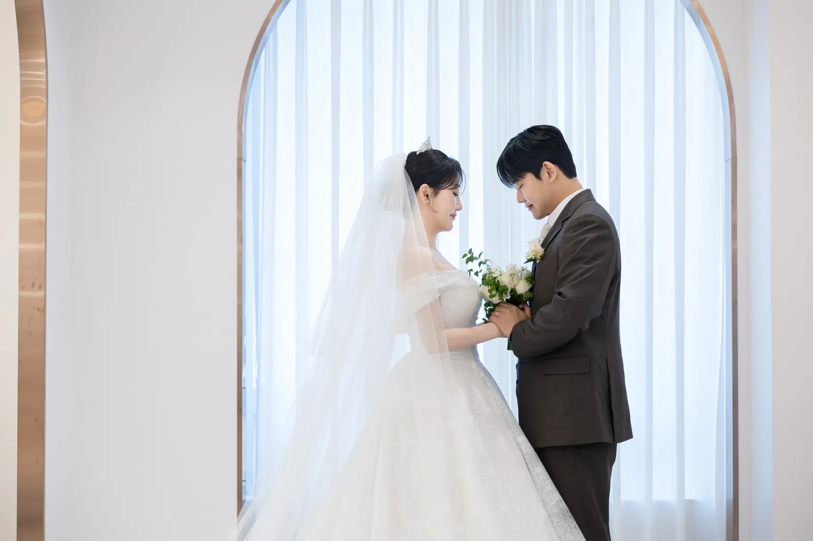 솔스퀘어컨벤션 신부대기실의 커튼 앞에서 부케를 함께 바라보는 신랑신부